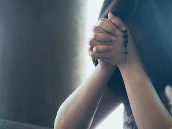 Close-up of woman praying with prayer beads