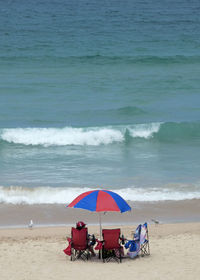 Deck chairs on beach against sea