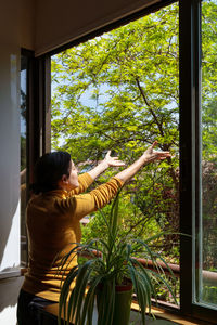 Rear view of woman standing by window