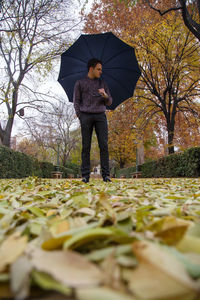 Man with umbrella standing on field during autumn