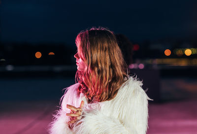 Rear view of woman with pink umbrella against sky at night