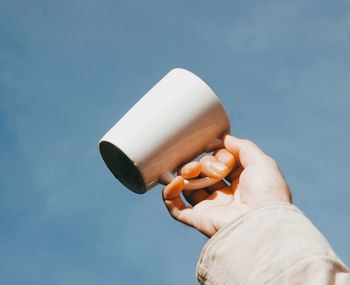 Low angle view of person holding camera against sky