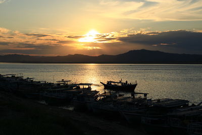 Boat moored in lake against sky during sunset