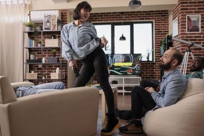 Full length of woman using phone while sitting on sofa at home