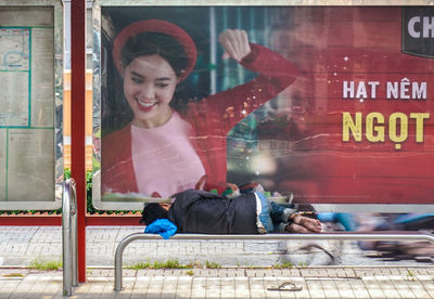 Happy woman sitting on glass against building
