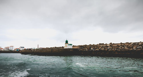 Lighthouse in sea against sky