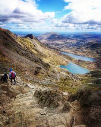 People on mountain against cloudy sky