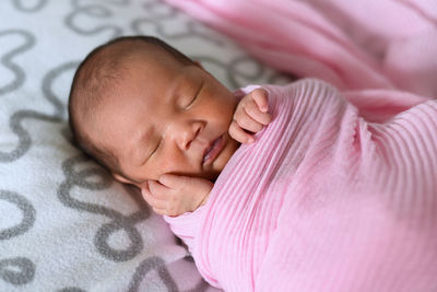 Close-up of baby girl sleeping on bed at home