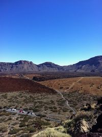 Scenic view of arid landscape against clear blue sky