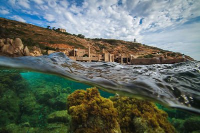 View of plants undersea with built structure on land against sky