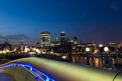 Illuminated cityscape against blue sky at night