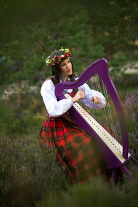 Young woman playing harp at forest