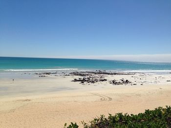 Scenic view of beach against clear blue sky