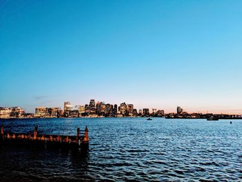 Sea by buildings against clear blue sky