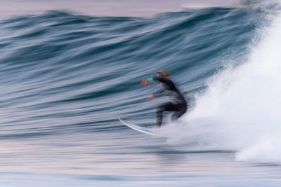 Blurred motion of person surfing in sea