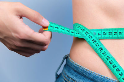 Midsection of woman holding tape measure