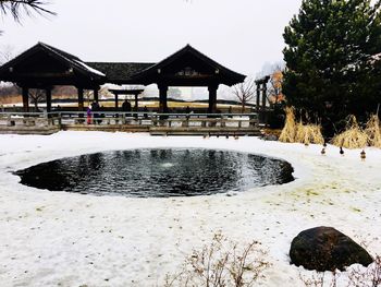 Gazebo by building against sky during winter