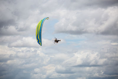 Low angle view of person paragliding against sky