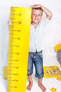 Portrait of cute smiling boy measuring height at home