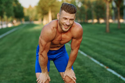 Portrait of shirtless man exercising on field