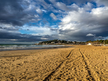 Scenic view of sandy beach against cloudy sky