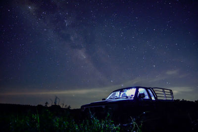 Illuminated car on field against sky at night