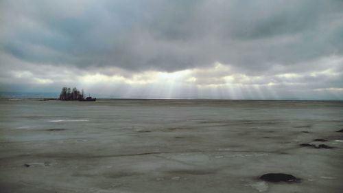 Scenic view of beach against cloudy sky