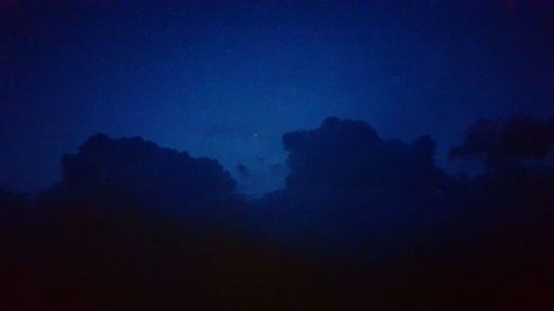 Low angle view of silhouette trees against blue sky