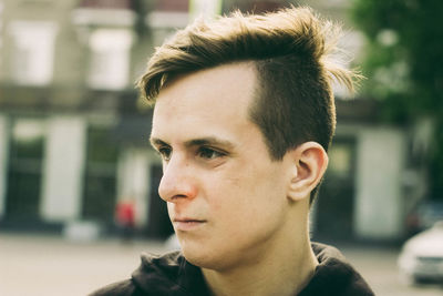 Close-up of thoughtful young man looking away in city