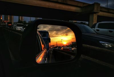 Cars on illuminated road against sky during sunset