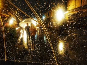 Illuminated street seen through wet glass window