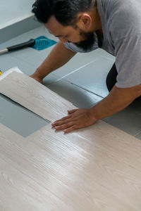 High angle view of man putting hardwood on floor