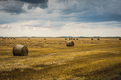 Hay bales on field against sky