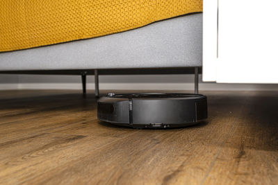 A modern robotic vacuum cleaner cleans vinyl panels under bedroom furniture. 