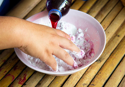 Close-up of hand holding ice cream on table