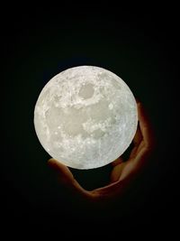 Close-up of hand holding crystal against black background