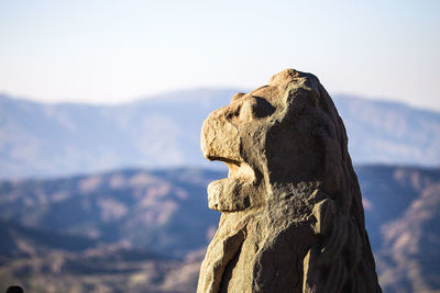 Close-up of animal statue on mountain against sky