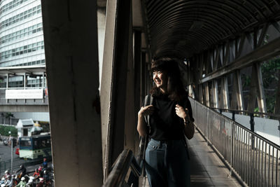 Young woman standing on bridge in city