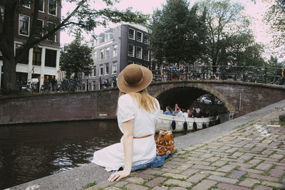 Woman sitting on canal with boat