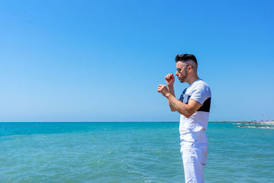 Full length of man standing in sea against clear blue sky