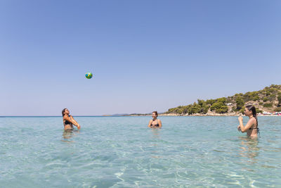 Happy teenagers playing volleyball in water at the vacation and fun