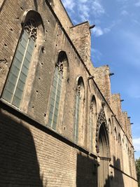 Low angle view of cross on building against sky