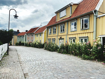 Cobbled street amidst a row of terrace houses against sky