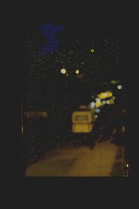 Illuminated city seen through wet glass window