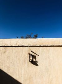 Text on wall by land against clear blue sky