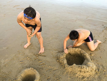 Full length of shirtless boys playing on sand at beach