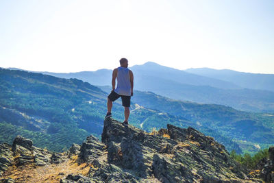 Rear view of man looking at mountains against sky