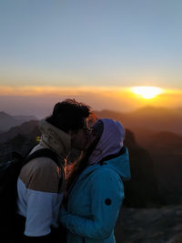 Couple kissing against sky during sunset