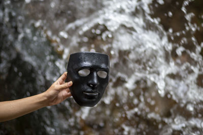 Human hand holding mask against water