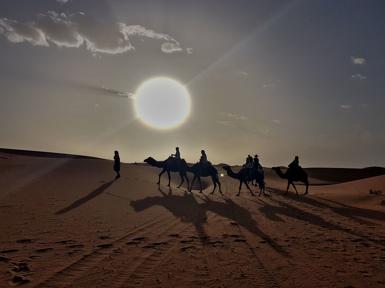 SILHOUETTE PEOPLE RIDING ON DESERT AGAINST SKY